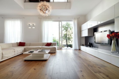 A living room with a sectional, TV, and unique pendant light.